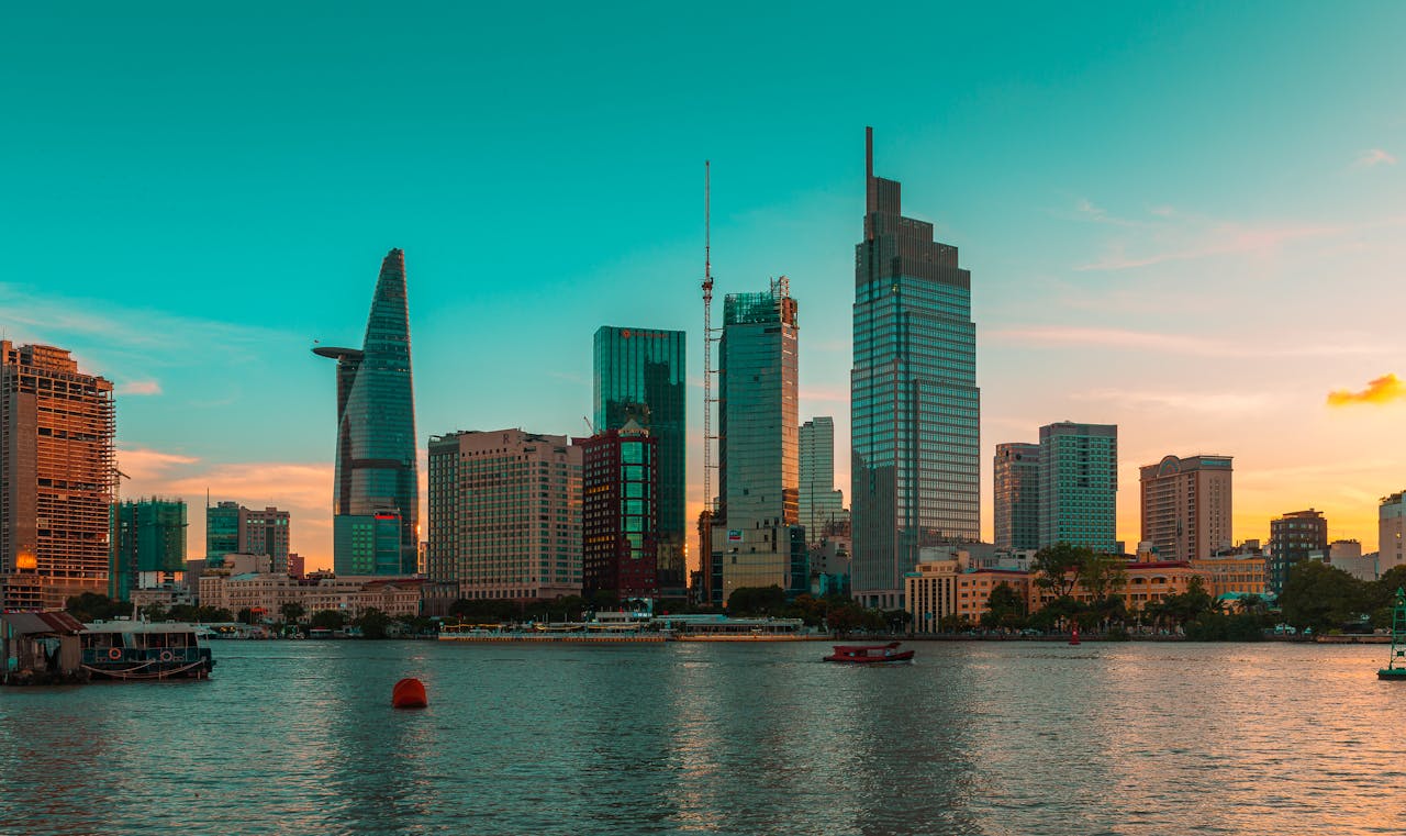 Stunning cityscape of Ho Chi Minh City with modern skyscrapers reflecting in the river at sunset.